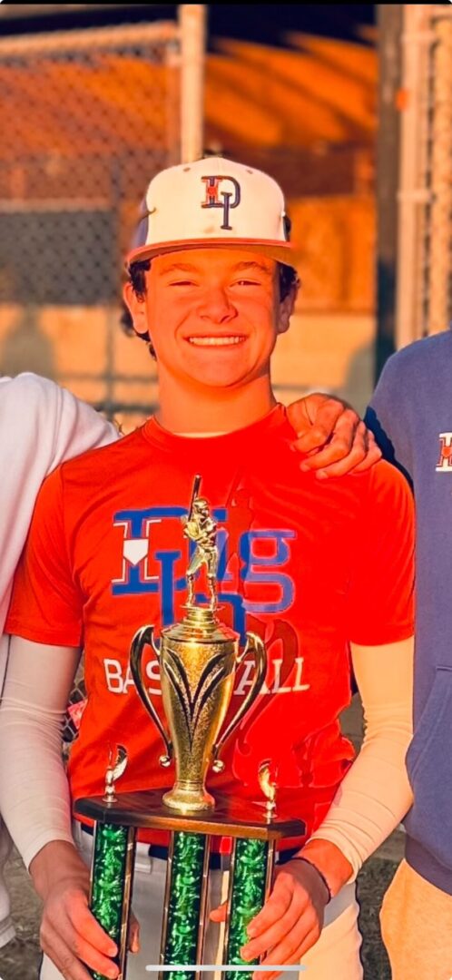 A young man holding a trophy in front of two other people.